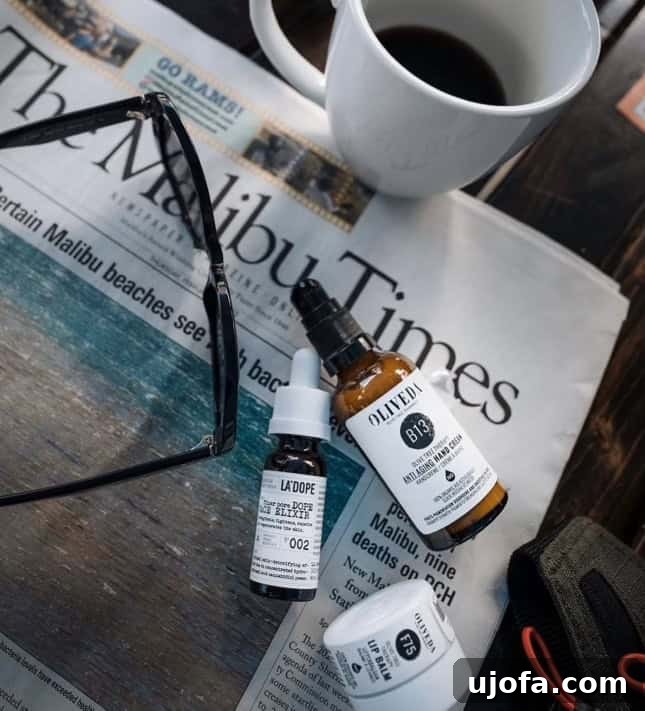 Oliveda skincare products on top of a Malibu Times newspaper next to a cup of coffee