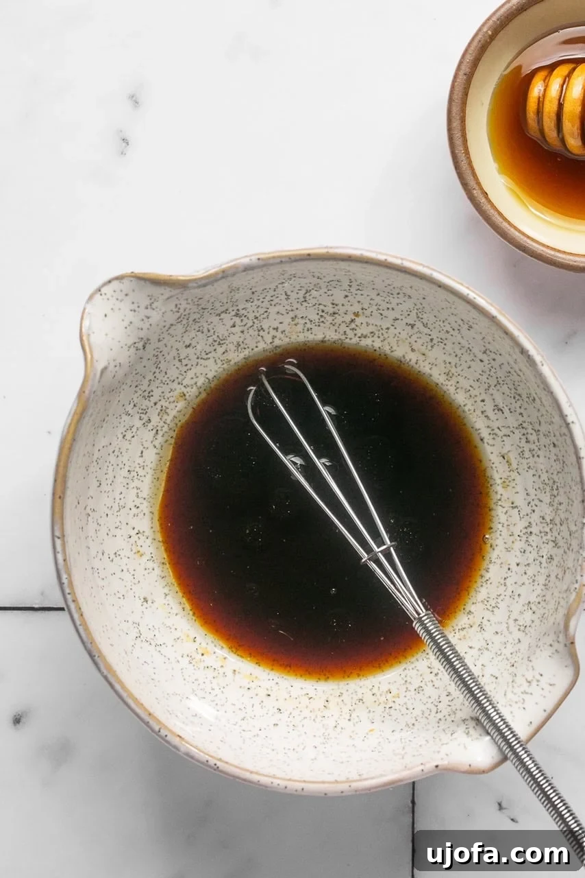 Refreshing Cucumber Carrot Crunch 4 A small glass bowl filled with a golden-brown, aromatic sesame dressing, freshly whisked and ready to be poured over a salad. The smooth texture hints at the delightful blend of sweet and savory notes.