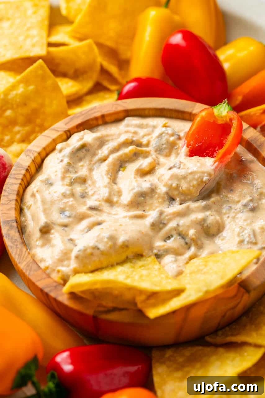 The Viral High-Protein Cottage Cheese Queso: Healthy Dip Perfection 6 dipping a mini bell pepper into a creamy dip