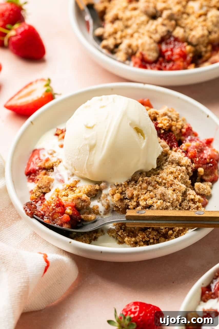 Sweet & Simple Gluten-Free Strawberry Crumble 3 A generous slice of warm strawberry crumble, perfectly plated alongside a melting scoop of vanilla ice cream, promising a delightful dessert experience.