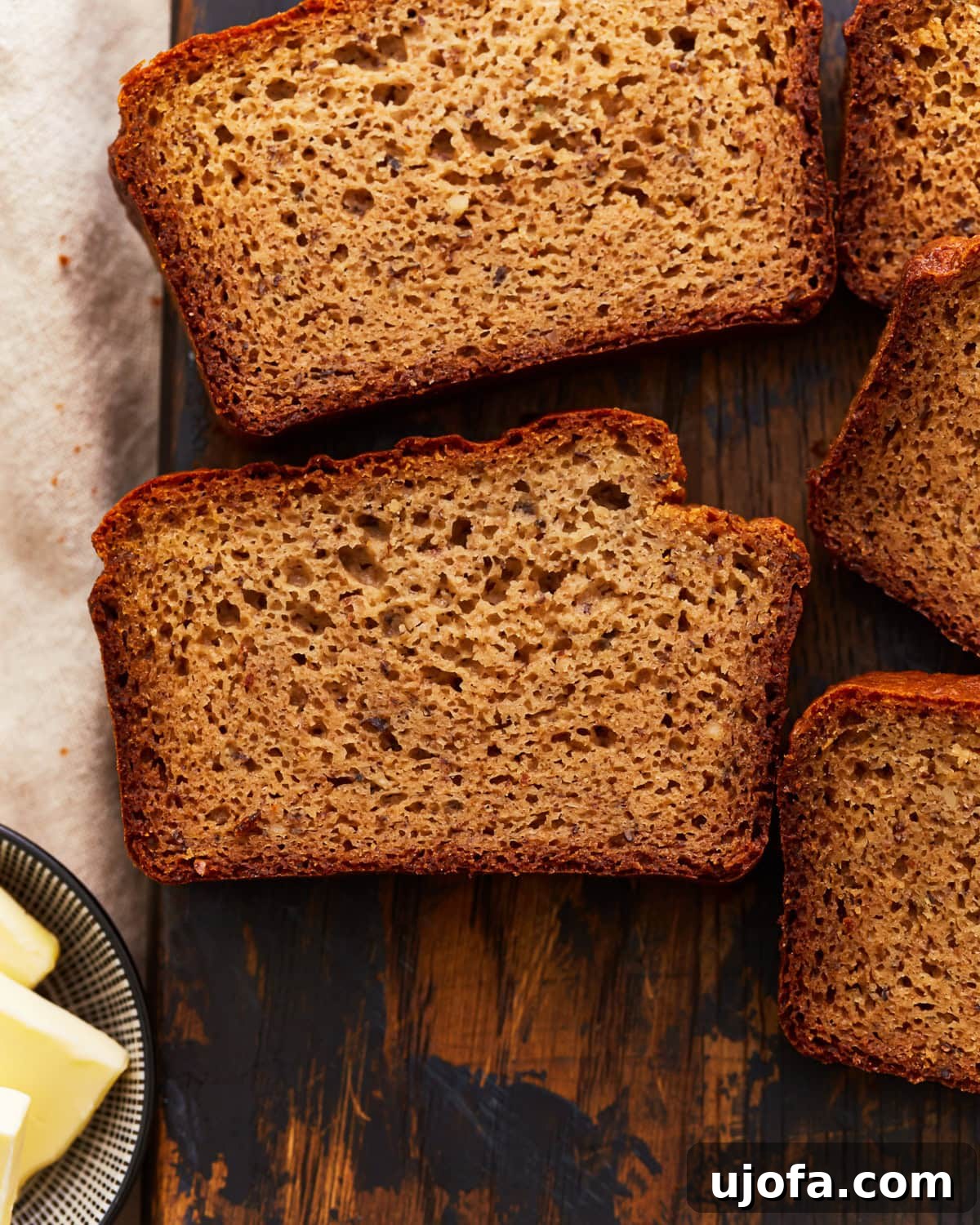 Grain-Free Almond Loaf 2 Stacked slices of moist almond flour bread on a rustic cutting board, showcasing its tender texture and golden crust, ready to be enjoyed.