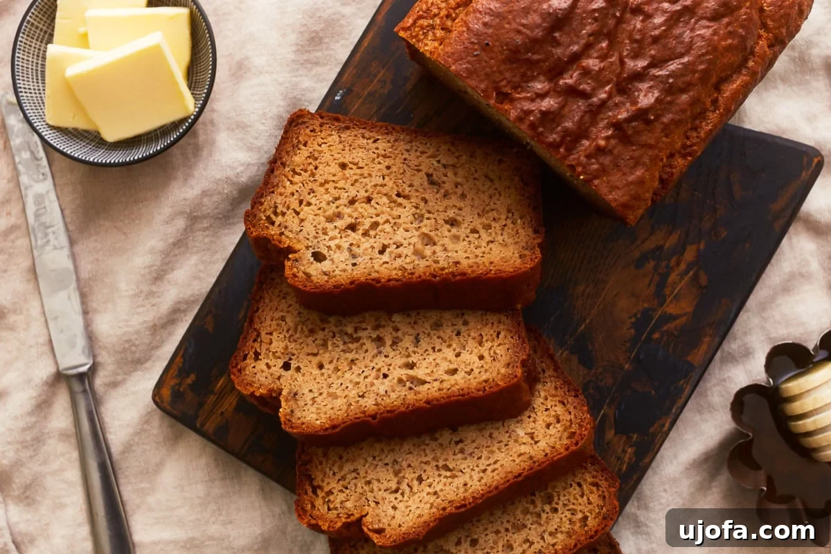 Grain-Free Almond Loaf 10 Overhead view of perfectly sliced almond flour bread on a rustic wooden cutting board, accompanied by a small dish of creamy butter and a butter knife, inviting a delightful tasting experience.