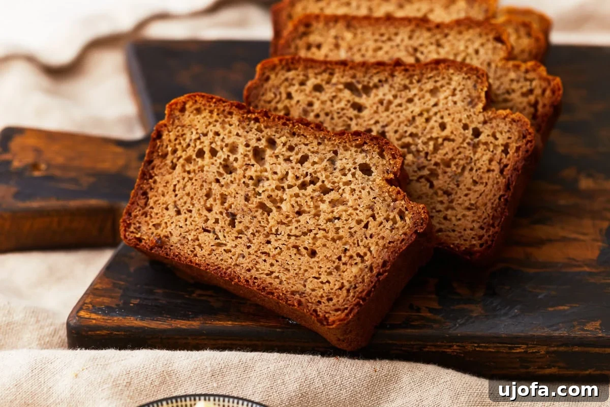 Grain-Free Almond Loaf 9 Close-up of several slices of almond flour bread arranged on a dark wooden cutting board, showing the soft, airy texture and golden crust, ready for a delicious meal or snack.