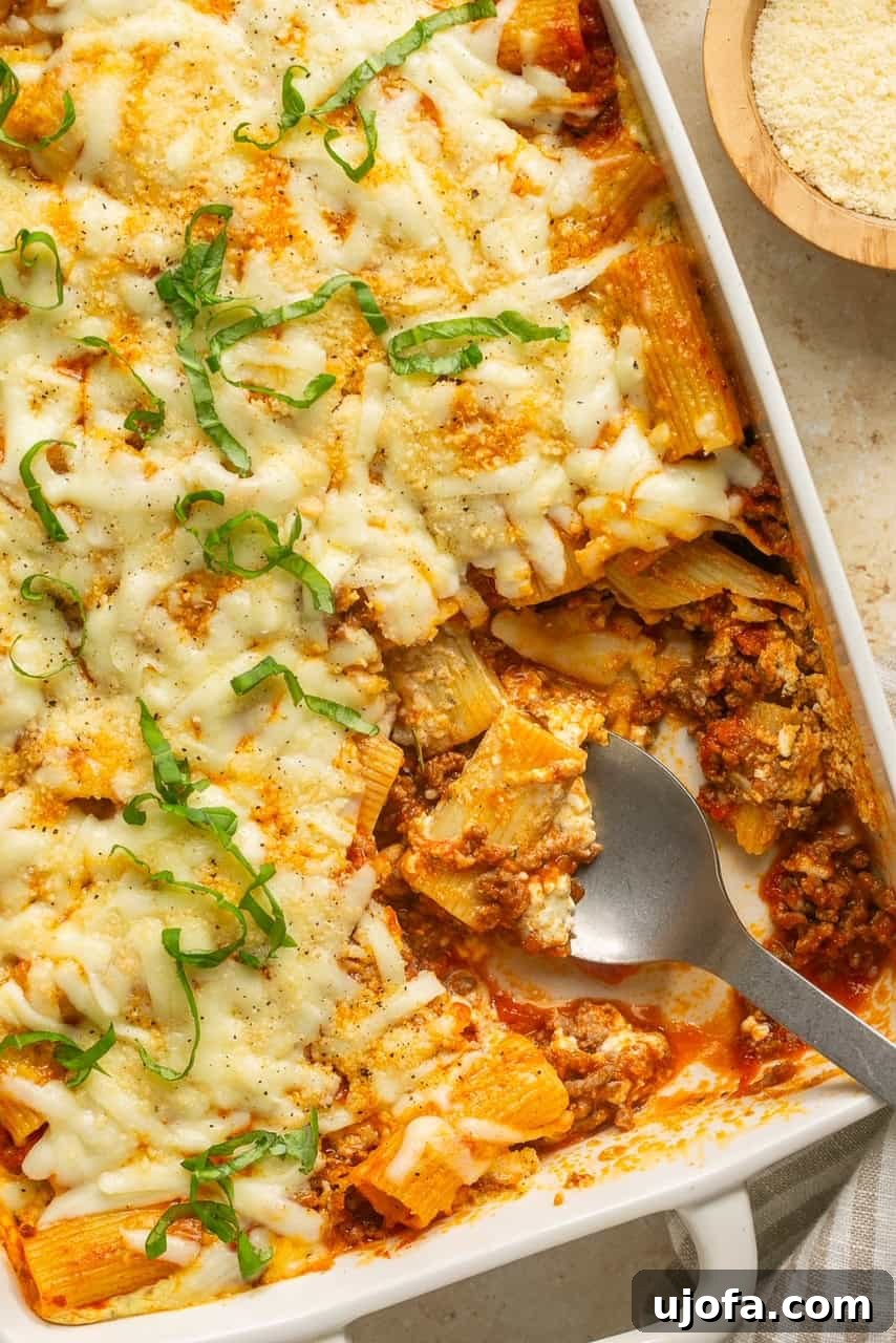 Super Simple Cheesy Lasagna Bake 2 A large dish of cheesy lazy lasagna with a portion scooped out, showcasing layers of pasta, meat sauce, and melted cheese.