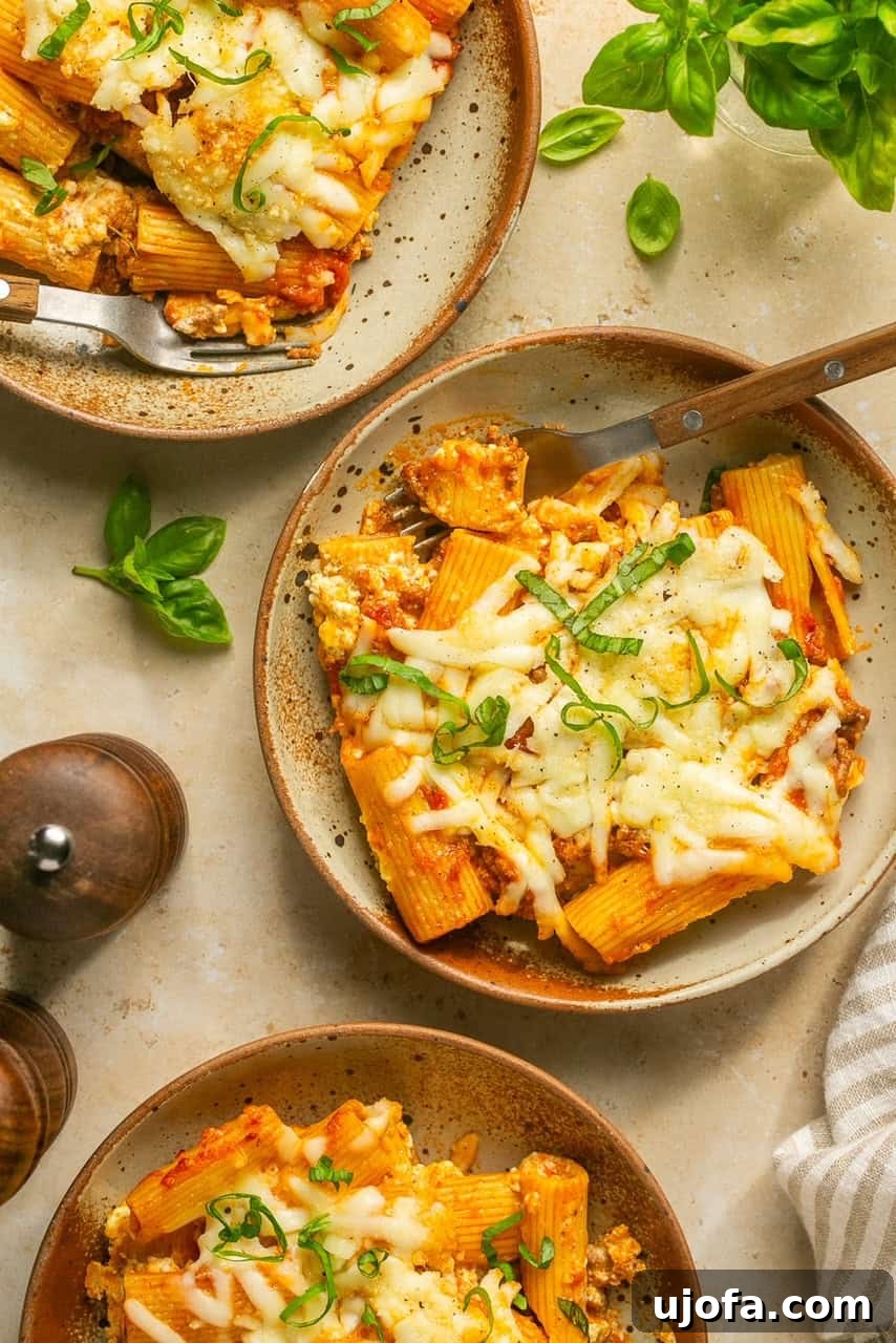 Super Simple Cheesy Lasagna Bake 7 A scoop of lazy lasagna on a white plate, ready to be eaten with a fork.