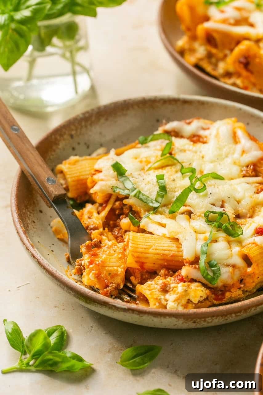 Super Simple Cheesy Lasagna Bake 8 An extreme close-up photo of a fork digging into a cheesy, saucy bite of lazy lasagna.