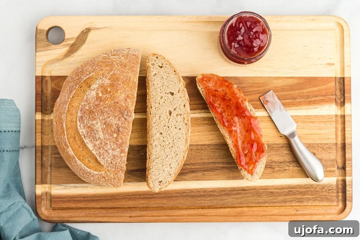 The Art of Gluten-Free Sourdough 2 A perfectly sliced gluten-free sourdough loaf resting on a rustic wood cutting board, accompanied by a jar of sweet jam and a knife, showcasing its soft crumb and golden crust.