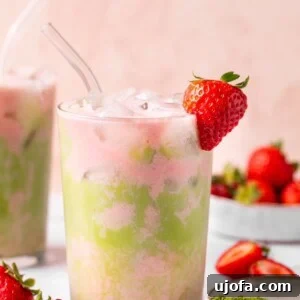 strawberry matcha tea over ice in a glass with a strawberry garnish