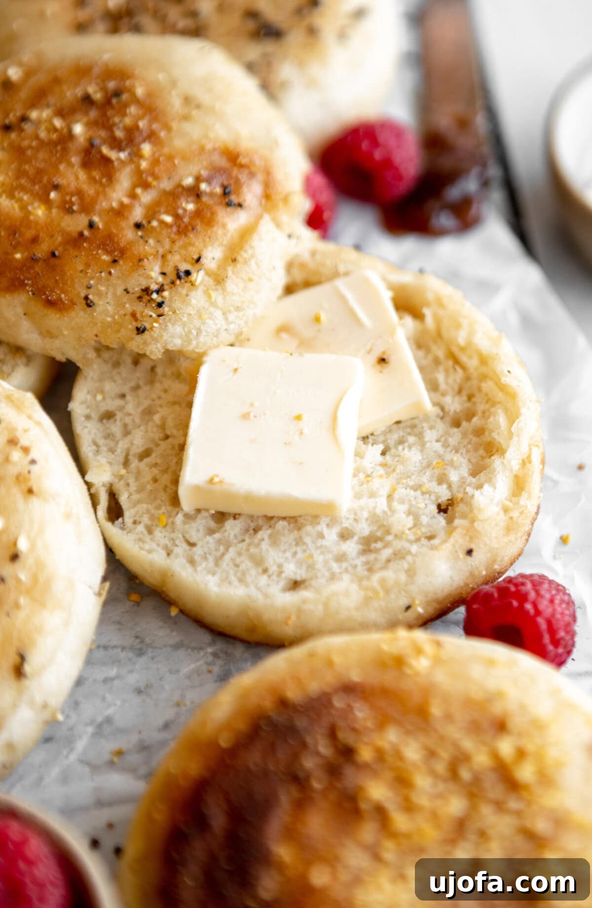 Gluten-free English muffin split open with pats of butter melting into its nooks and crannies.