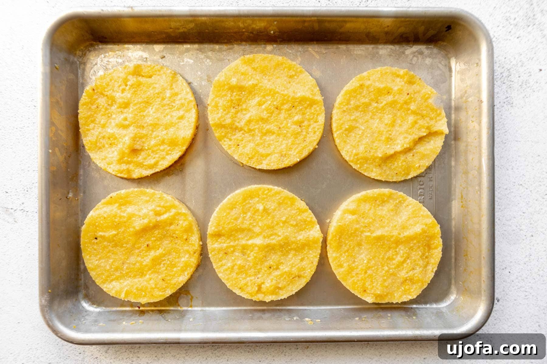 Golden Fried Grits 8 Chilled grits neatly cut into circular shapes on a baking sheet, ready for frying.