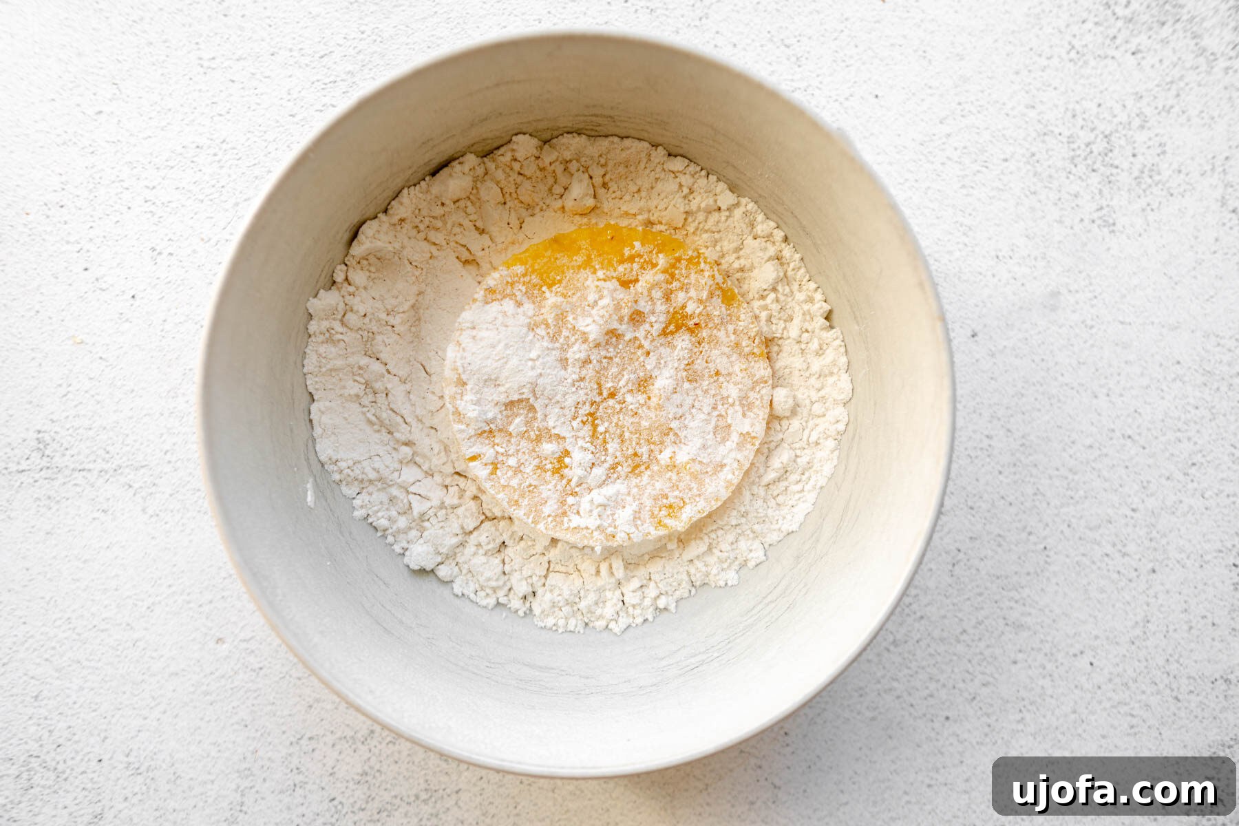 Golden Fried Grits 9 A single grit cake being dipped and coated in gluten-free flour in a shallow bowl.