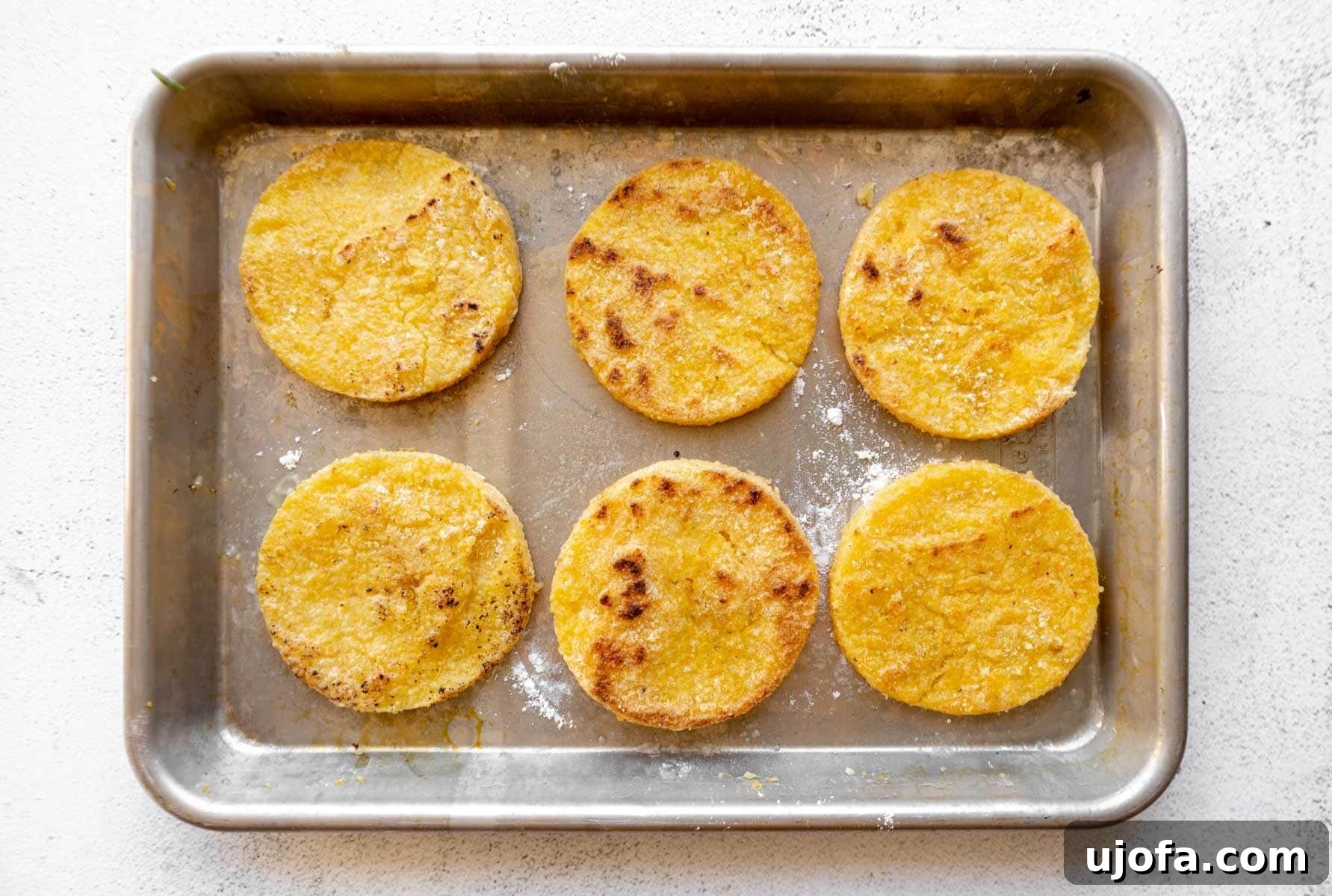 Golden Fried Grits 10 Several grit cakes arranged on a baking tray, coated and ready for pan-frying.