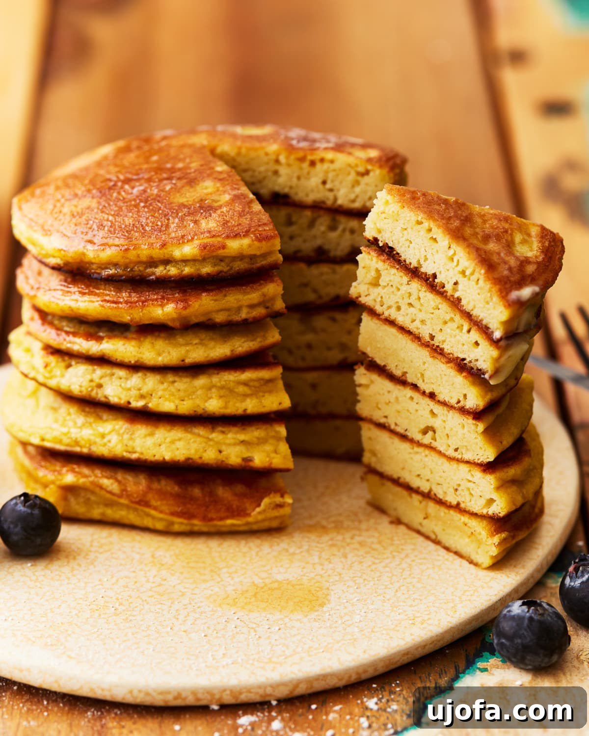 Close-up of a stacked coconut flour pancake with a wedge cut out, revealing its light and airy internal texture.