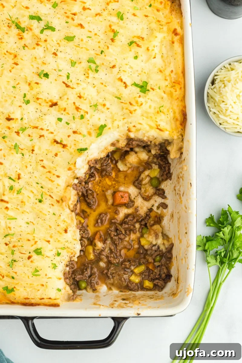 Hearty Gluten-Free Shepherd's Pie 6 A gluten-free shepherd's pie baking dish with a portion scooped out, revealing the rich layers of meat, vegetables, and golden potato topping.