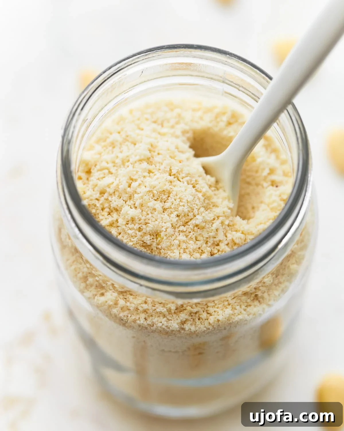 Freshly made almond flour in a mason jar with a spoon, highlighting its fine texture.