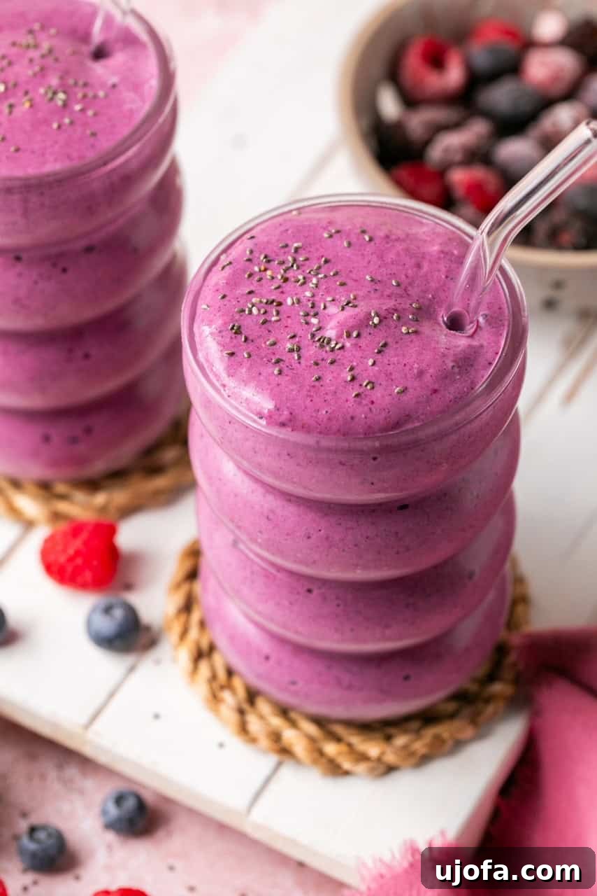 Two cottage cheese smoothies with cottage cheese and frozen berries in glass cups with glass straws, highlighting the creamy texture and vibrant color.