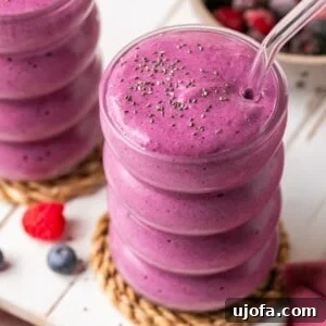 Two protein smoothies with cottage cheese and frozen berries in glass cups with glass straws