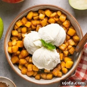 caramelized apples in a bowl topped with vanilla ice cream and mint surrounded by apples