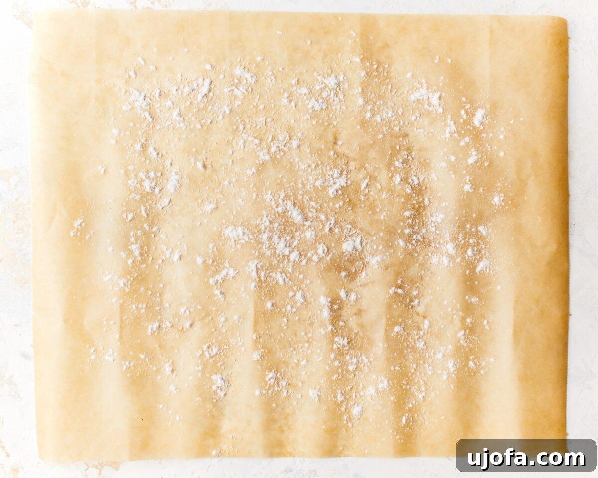 A piece of parchment paper evenly sprinkled with gluten-free flour, forming a circle, indicating readiness for shaping pizza dough.