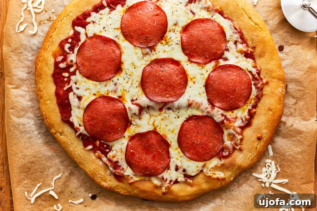 A fully baked gluten-free pepperoni pizza on parchment paper, with melted cheese and crispy pepperoni on a golden crust, looking perfectly cooked and inviting.