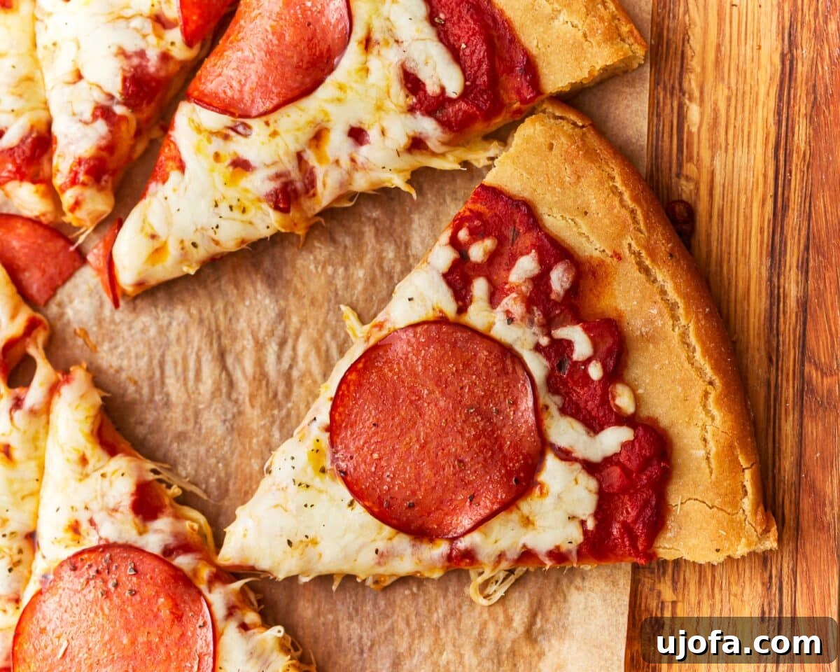 A close-up view of a freshly sliced gluten-free pepperoni pizza resting on a wooden cutting board, with one slice pulled away to reveal the thick, airy crust, melted cheese, and savory pepperoni.