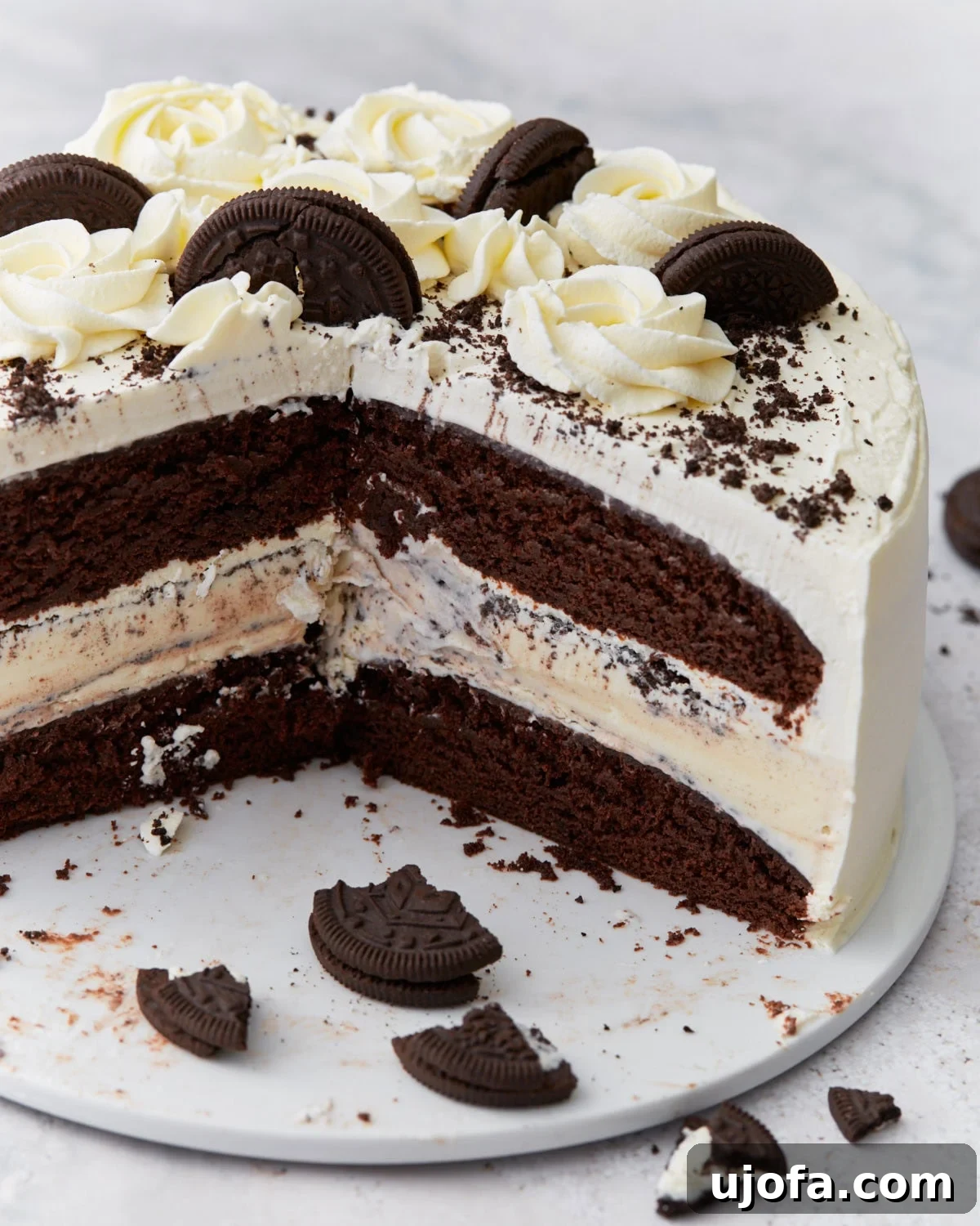 Delicious Gluten-Free Cake Delights 20 A layered gluten-free chocolate ice cream cake sliced to reveal chocolate cake layers, a vanilla ice cream center with cookie pieces, whipped cream frosting, and decorative chocolate cookies and rosettes on top.
