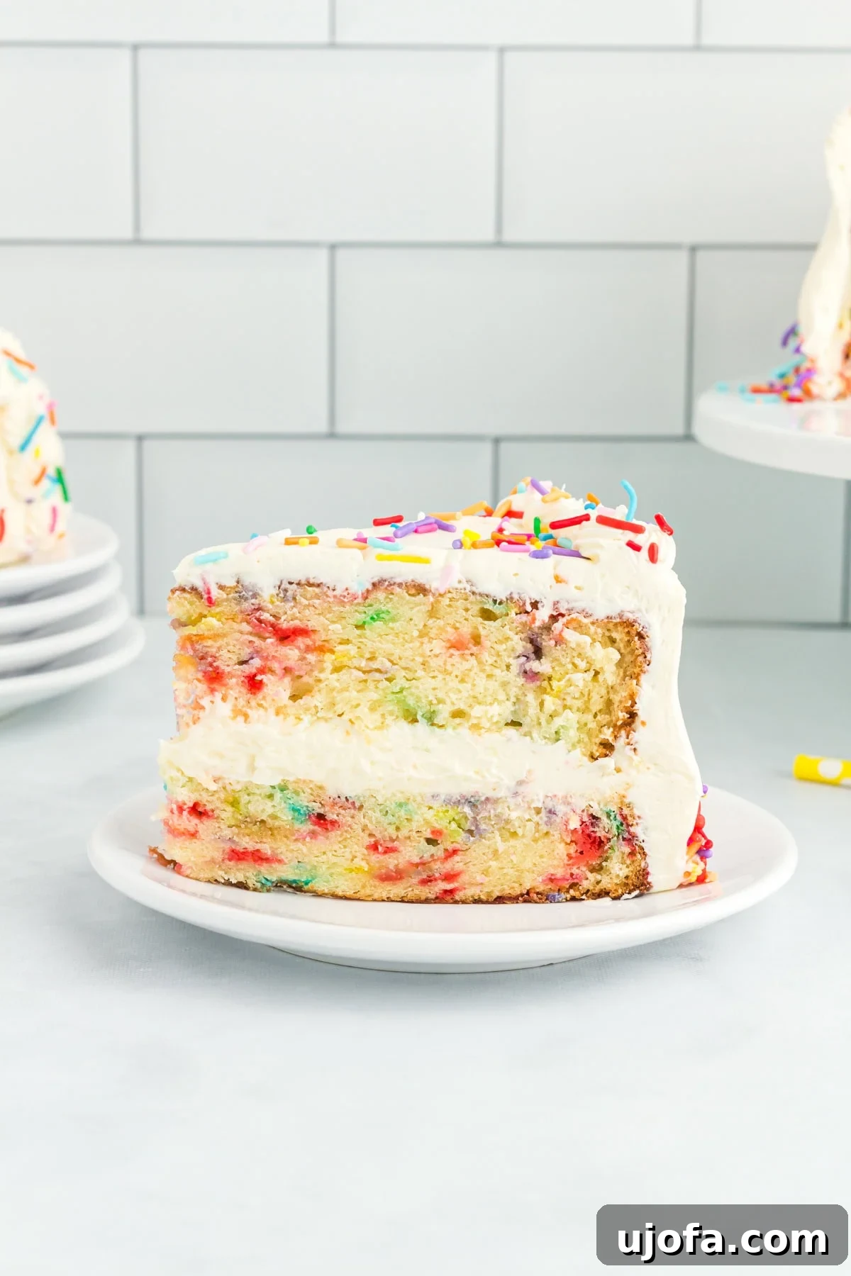 Delicious Gluten-Free Cake Delights 6 A close-up of a slice of gluten-free funfetti cake with white buttercream frosting and rainbow sprinkles, showing the colorful sprinkle-filled layers inside.