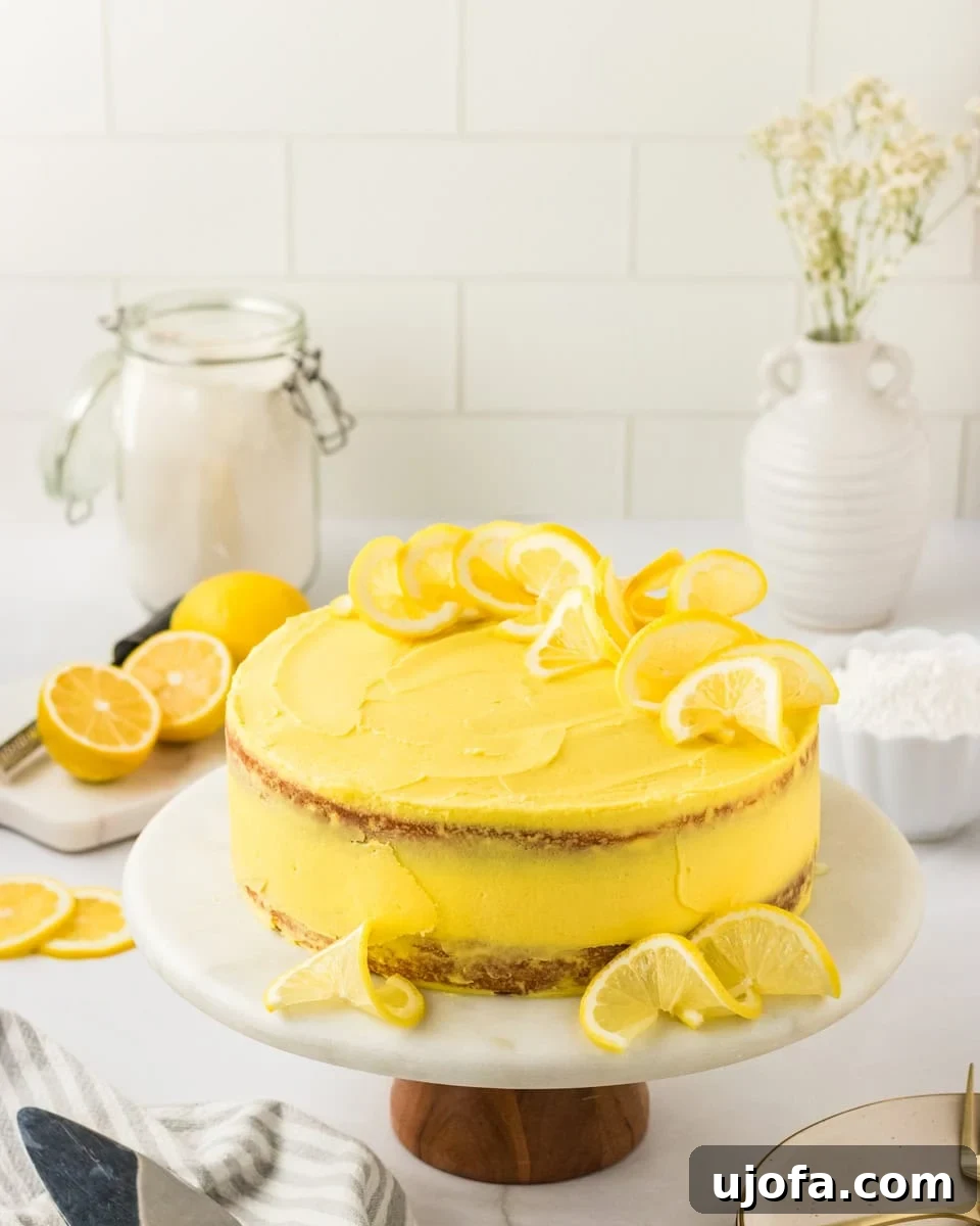 Delicious Gluten-Free Cake Delights 10 A frosted gluten-free lemon cake on a marble cake stand, decorated with lemon slices on top and around the base. The cake has a bright yellow frosting and a rustic, semi-naked finish. Fresh lemons, a jar of flour, and white ceramic vases are styled in the background.
