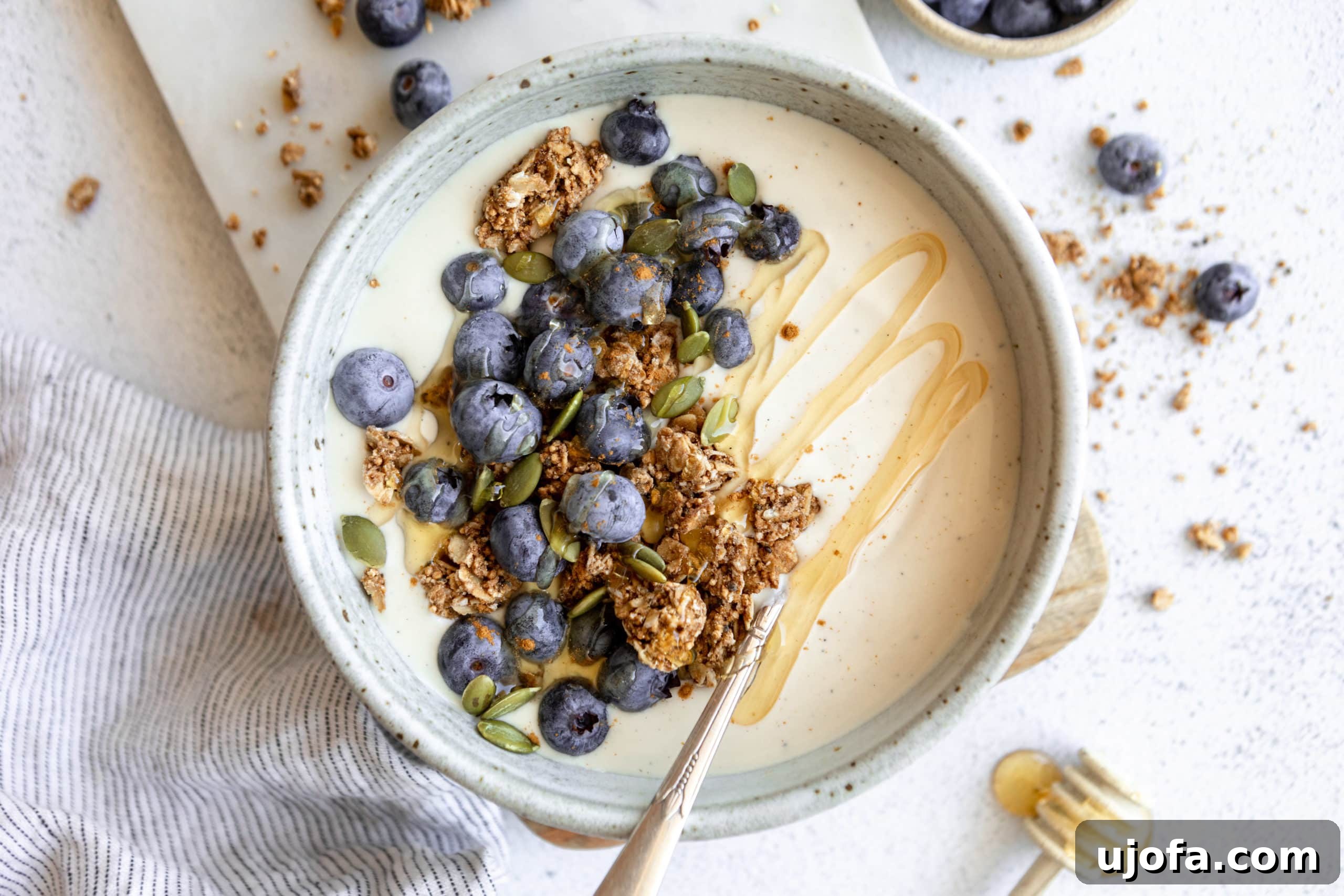 A close-up of creamy coconut yogurt in a white bowl, garnished with fresh fruits and crunchy granola, ready for a healthy breakfast.