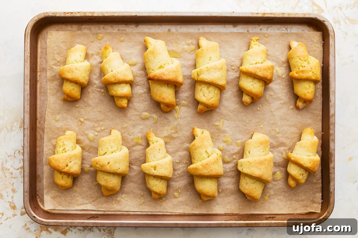 Buttery Gluten-Free Crescent Rolls 10 freshly baked, golden-brown gluten-free crescent rolls on a parchment-lined baking sheet.