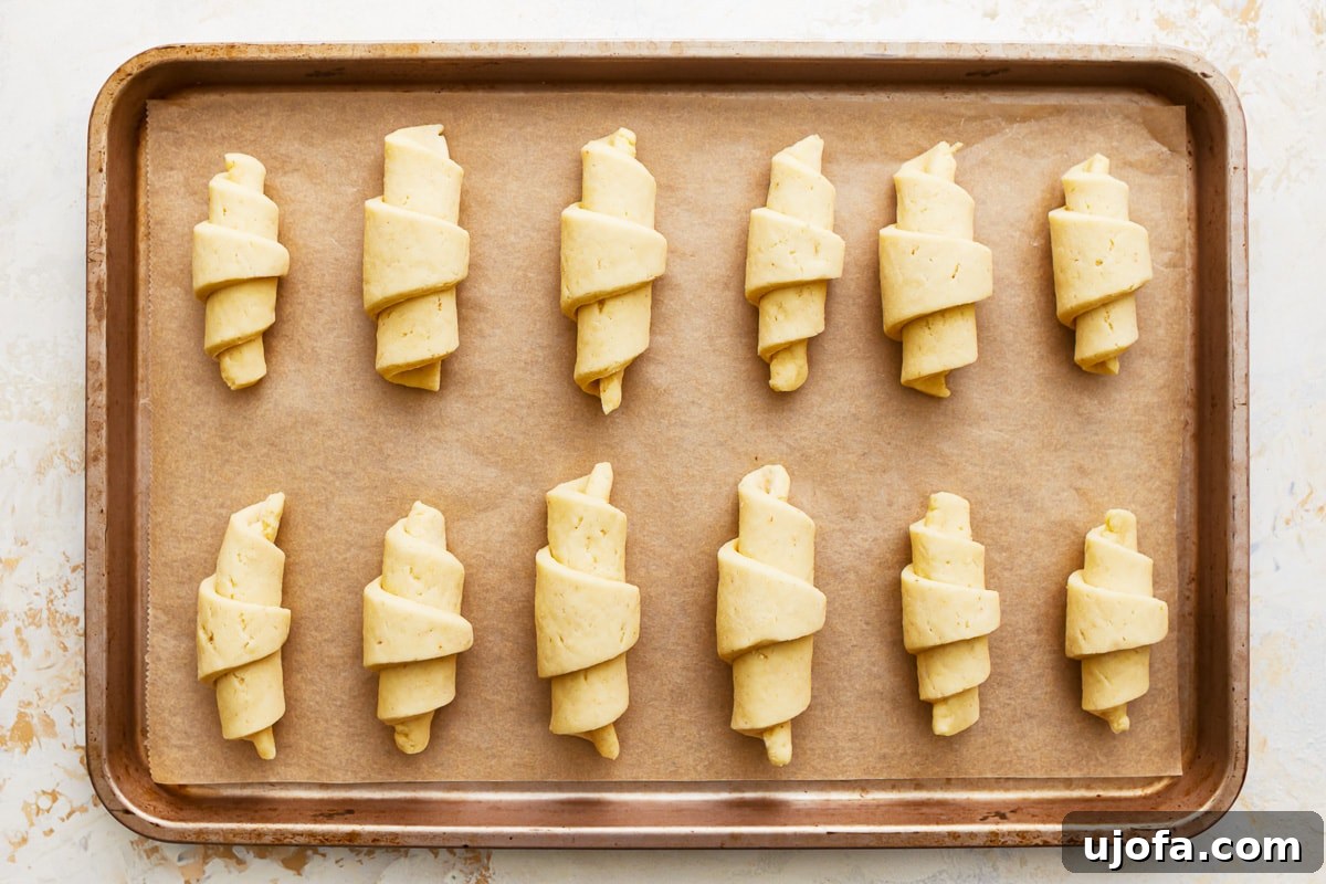 Buttery Gluten-Free Crescent Rolls 9 unbaked gluten-free crescent rolls arranged on a parchment-lined baking sheet.