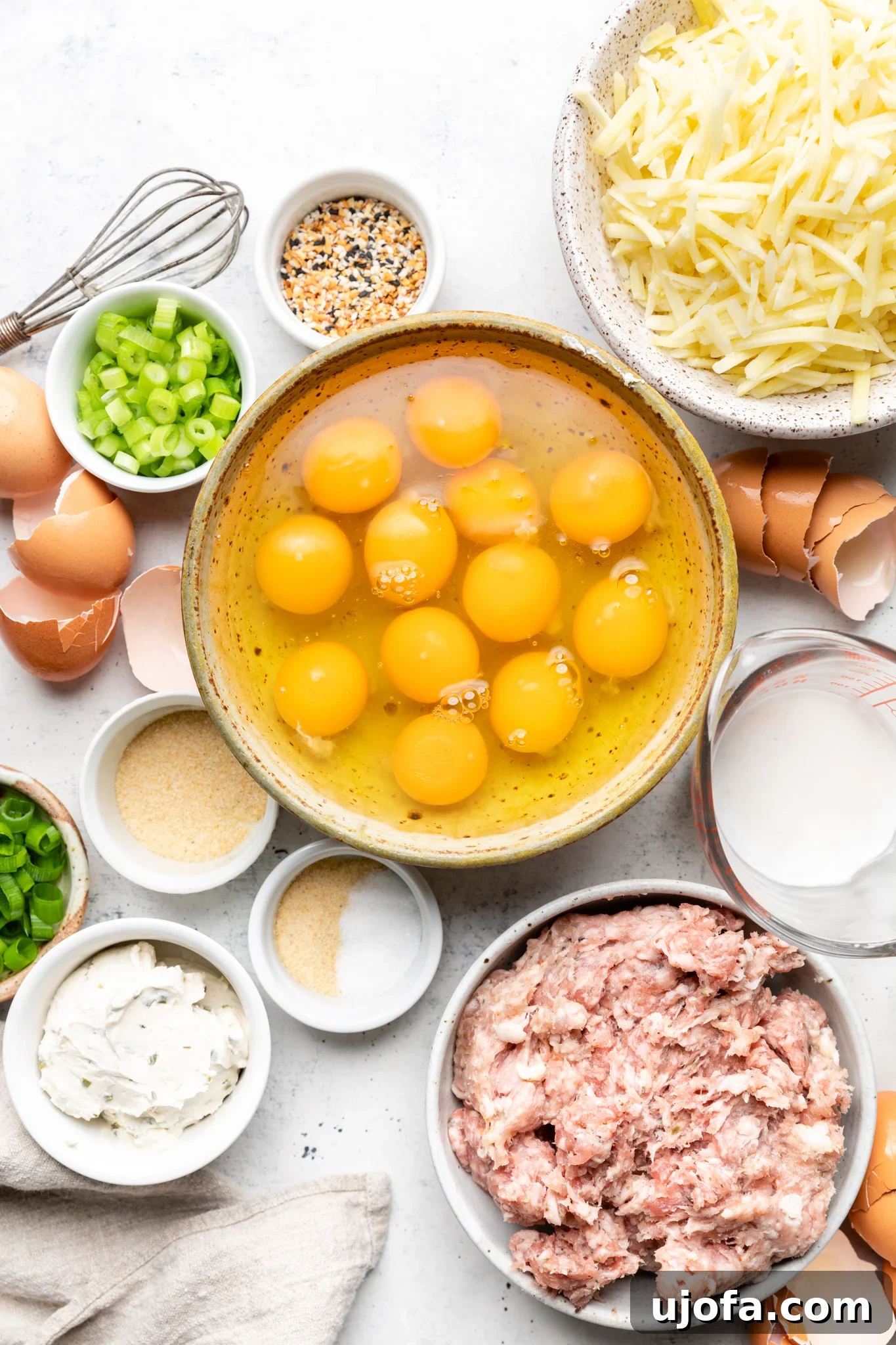 Wholesome Breakfast Casserole Gluten Free Dairy Free 3 Ingredients laid out for paleo sausage hash brown breakfast casserole, including eggs, sausage, green onions, dairy-free cream cheese, and seasonings.
