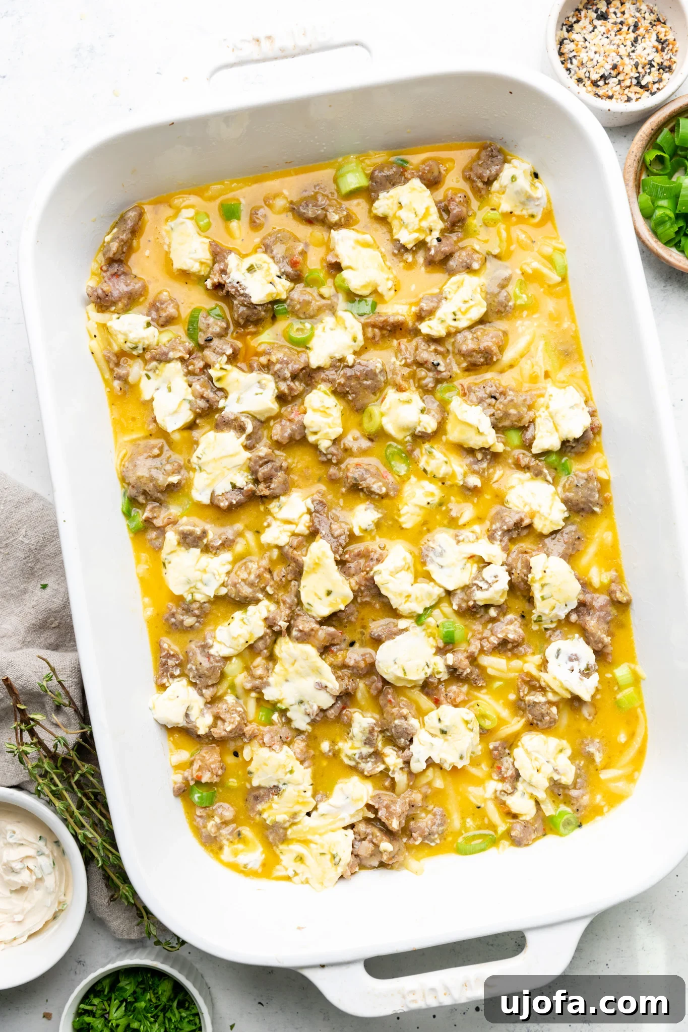 Wholesome Breakfast Casserole Gluten Free Dairy Free 6 Egg mixture poured over hash browns, sausage, and green onions in a white casserole dish.