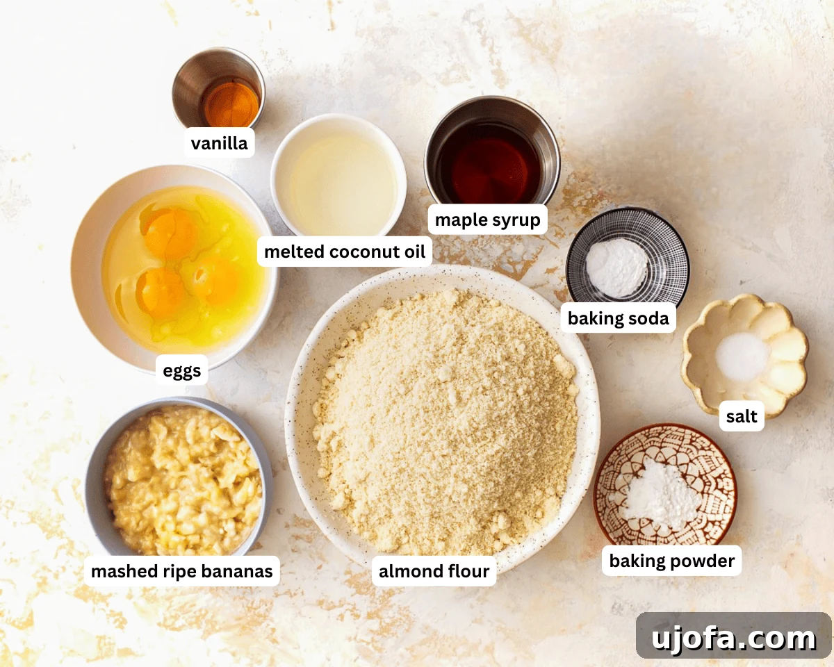 Ingredients for almond flour banana muffins laid out on a table: bananas, eggs, coconut oil, maple syrup, vanilla, almond flour, baking soda, baking powder, and salt.