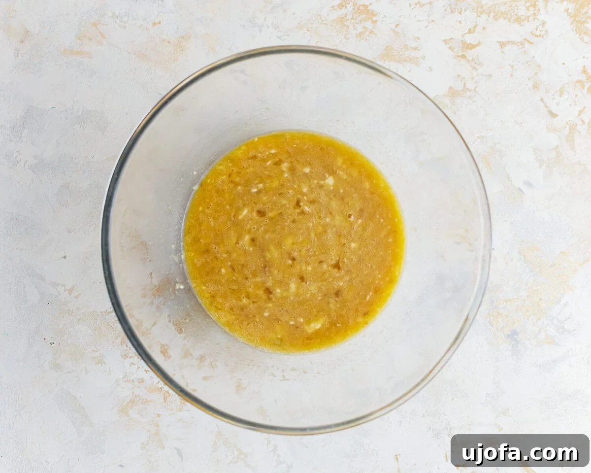 A brown liquid mixture in a glass bowl, representing the wet ingredients.