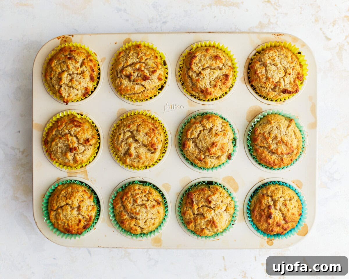 Overhead view of golden-brown almond flour banana muffins baking in a muffin tin.