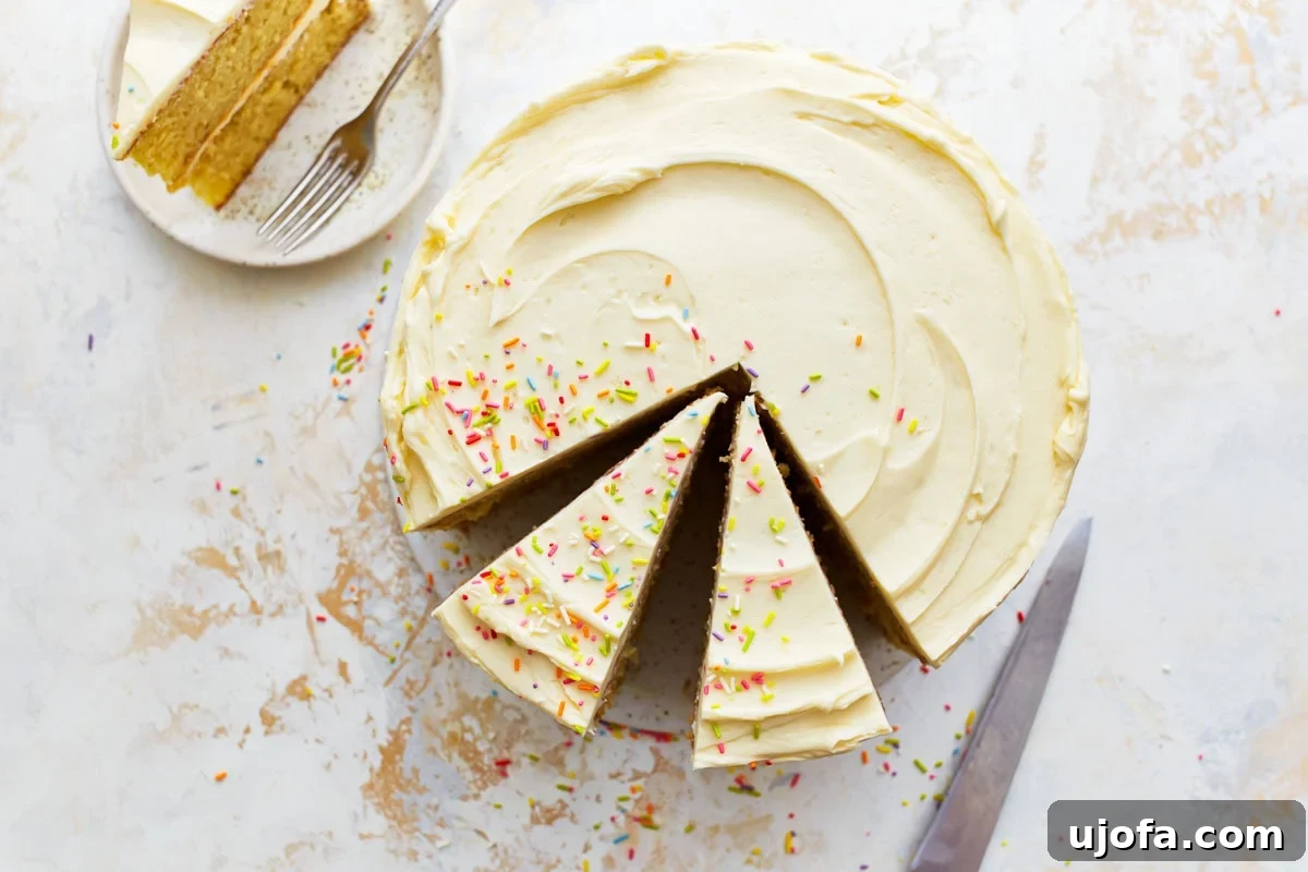 Served Gluten-Free Vanilla Cake A frosted round gluten-free vanilla cake with sprinkles, and a slice served on a plate with a fork.