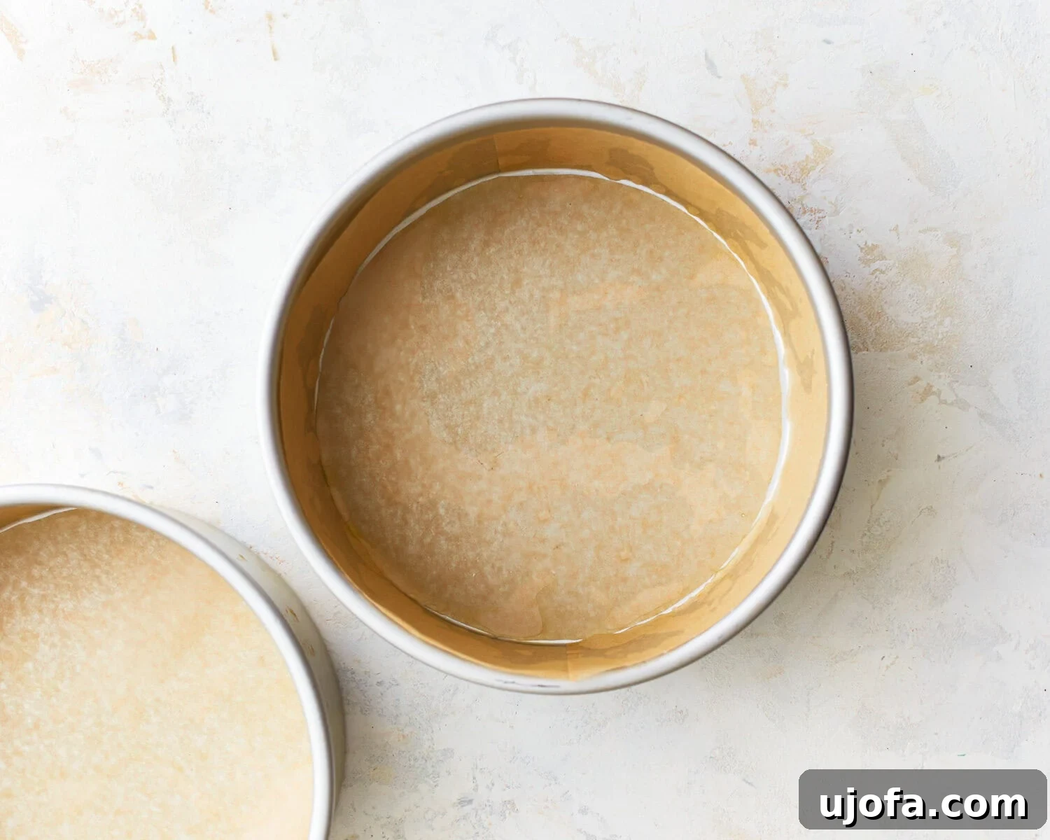Prepared Cake Pans Two 8-inch round cake pans lined with parchment paper.