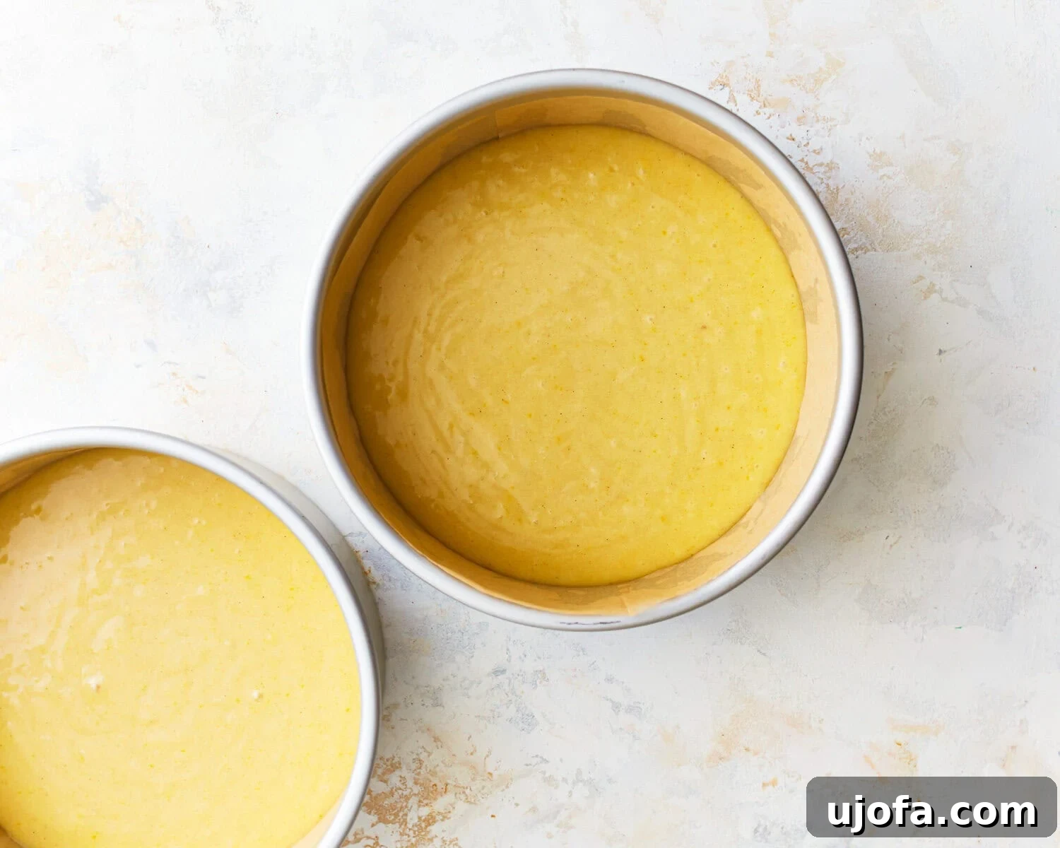 Batter in Cake Pans Gluten-free vanilla cake batter evenly divided into two cake pans.
