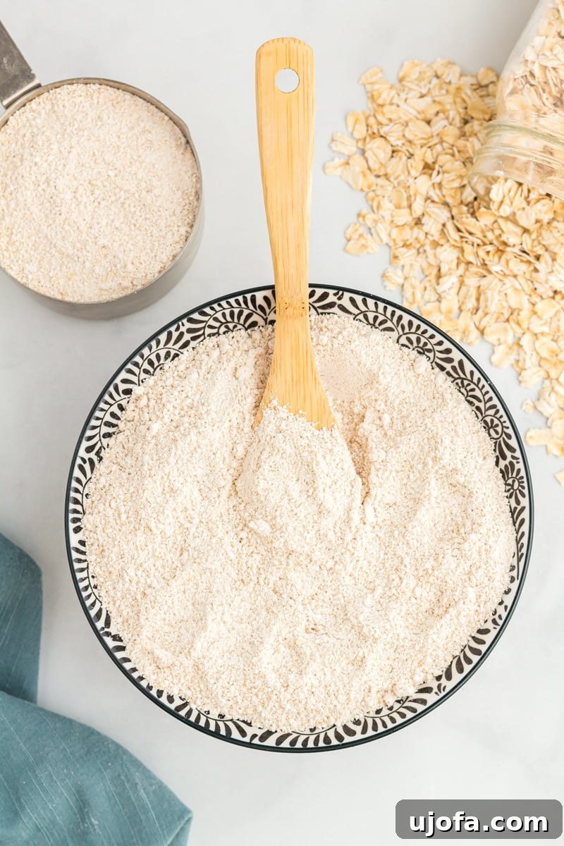 Crafting Homemade Oat Flour 2 overhead view of oat flour in a decorative serving bowl with a wooden spoon.