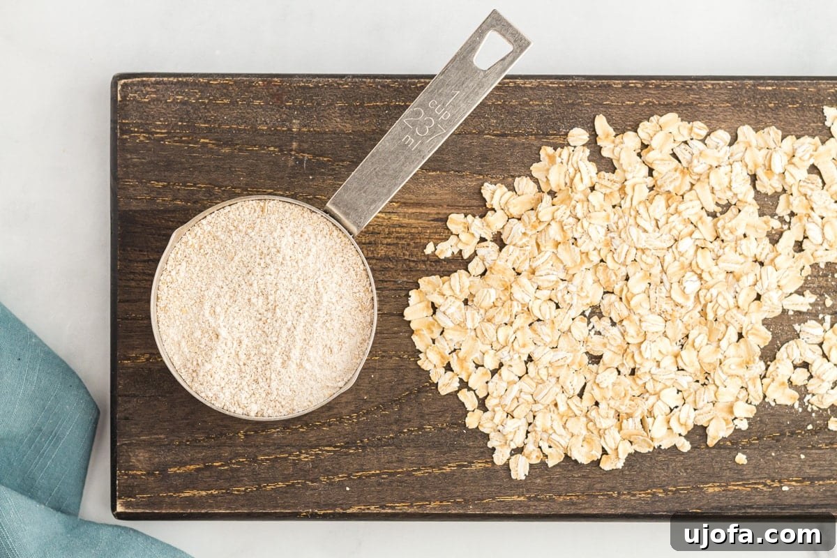 Crafting Homemade Oat Flour 4 overhead view of oat flour in a measuring cup on a wooden cutting board with whole oats.