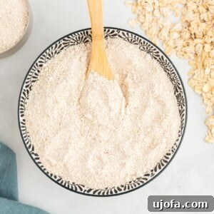 overhead view of oat flour in a decorative serving bowl with a wooden spoon.