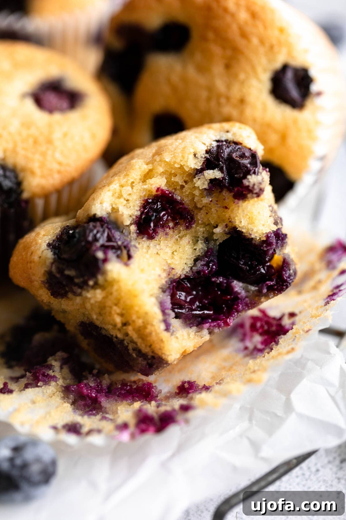 close-up view of a bitten almond flour blueberry muffin, showing its moist texture and vibrant blueberries.