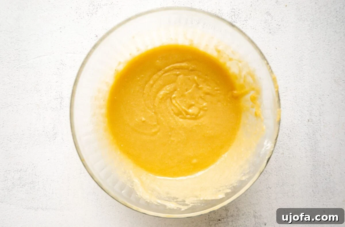 A clear glass bowl showing the wet ingredients mixed with almond flour, forming a thick, creamy batter, ready for the next step in the muffin-making process.
