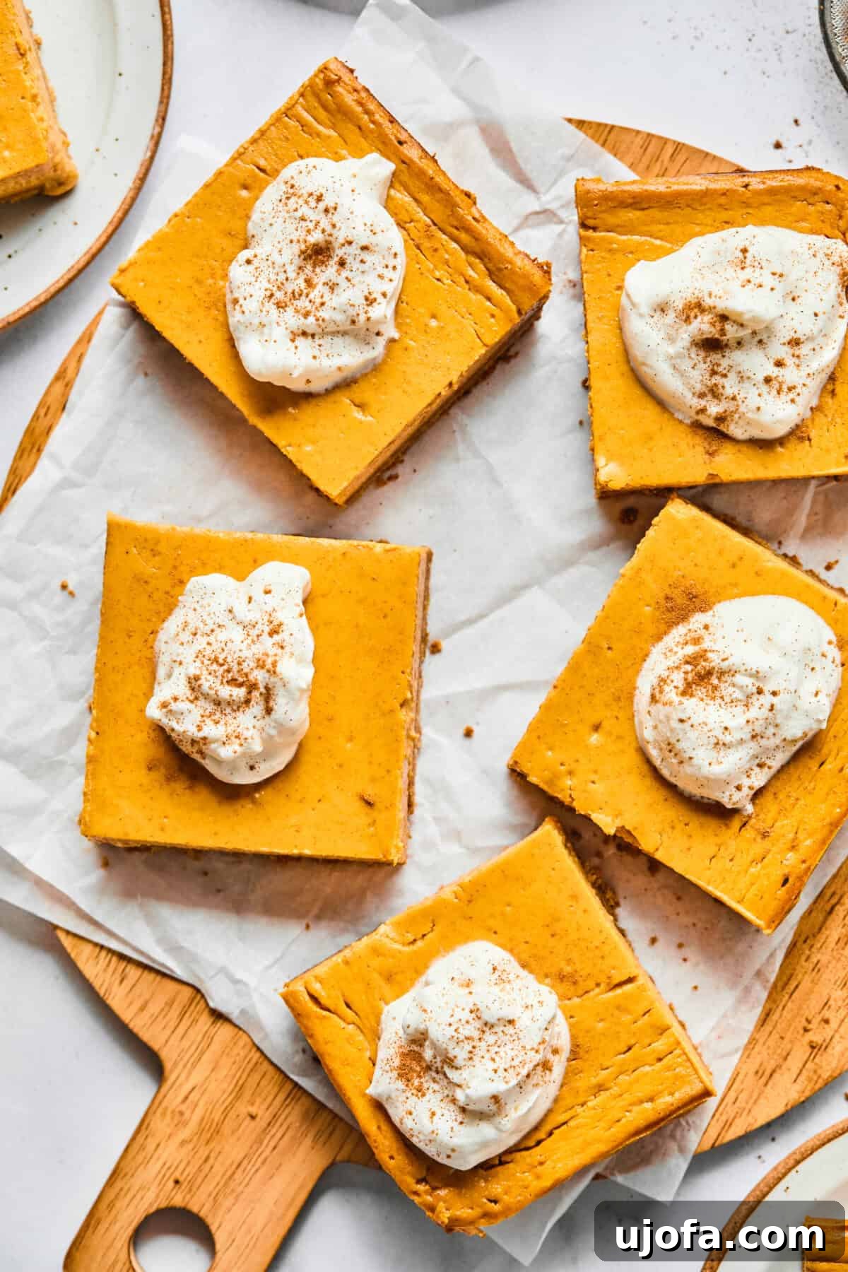 Easy Protein-Packed Pumpkin Cheesecake Bars 11 pumpkin pie cheesecake bars on a cutting board with parchment paper