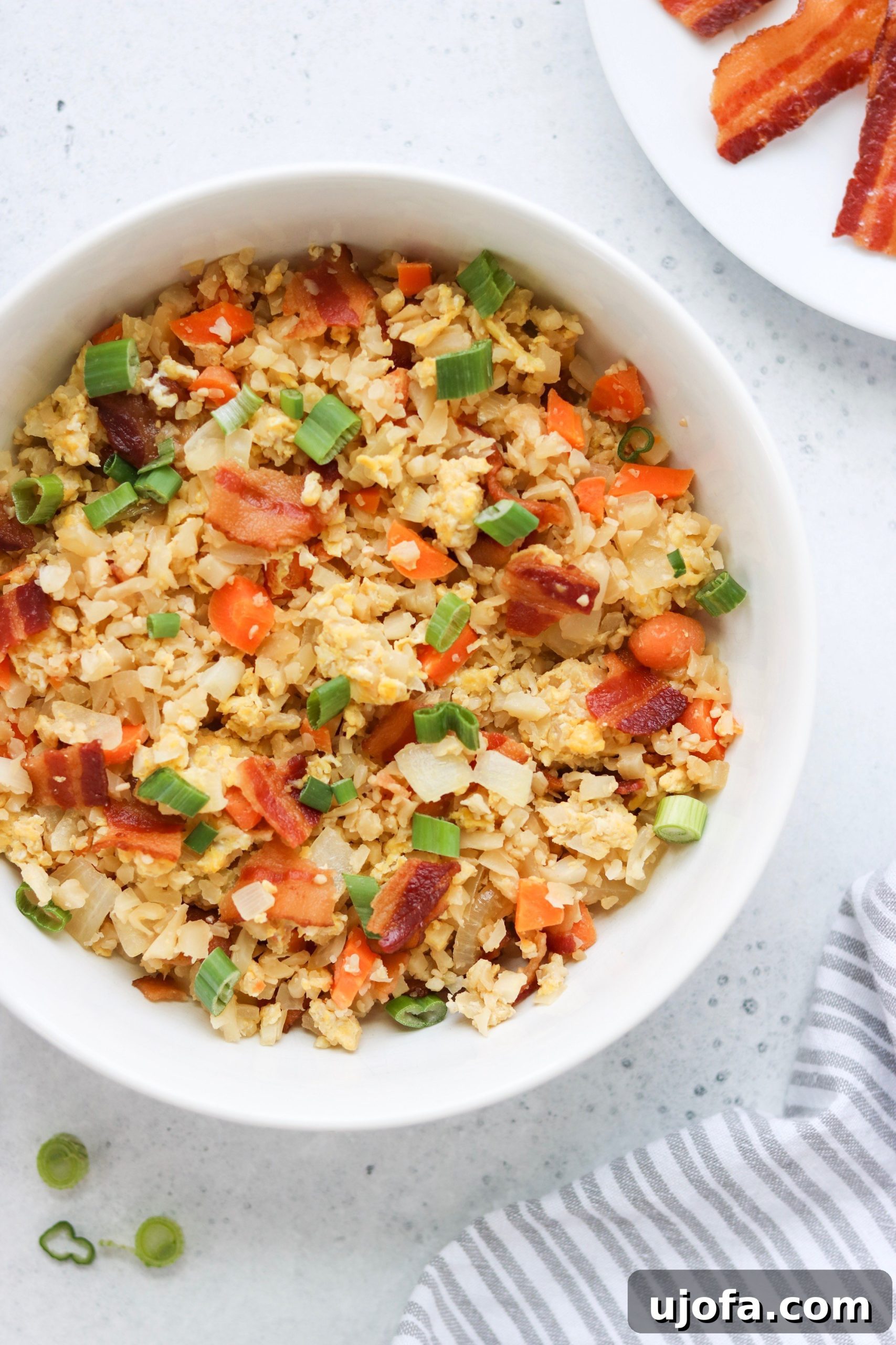 A close-up shot of the finished Paleo Breakfast Fried Rice in a pan, steaming and ready to be served, topped with green onions.