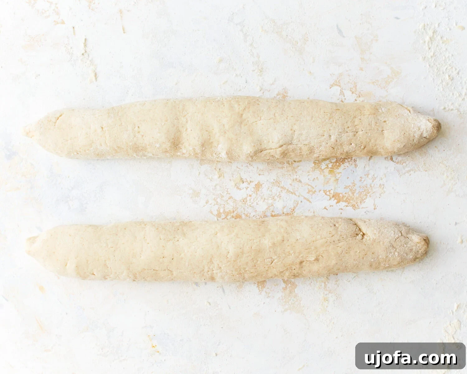 Gluten-free baguette dough shaped into two logs.