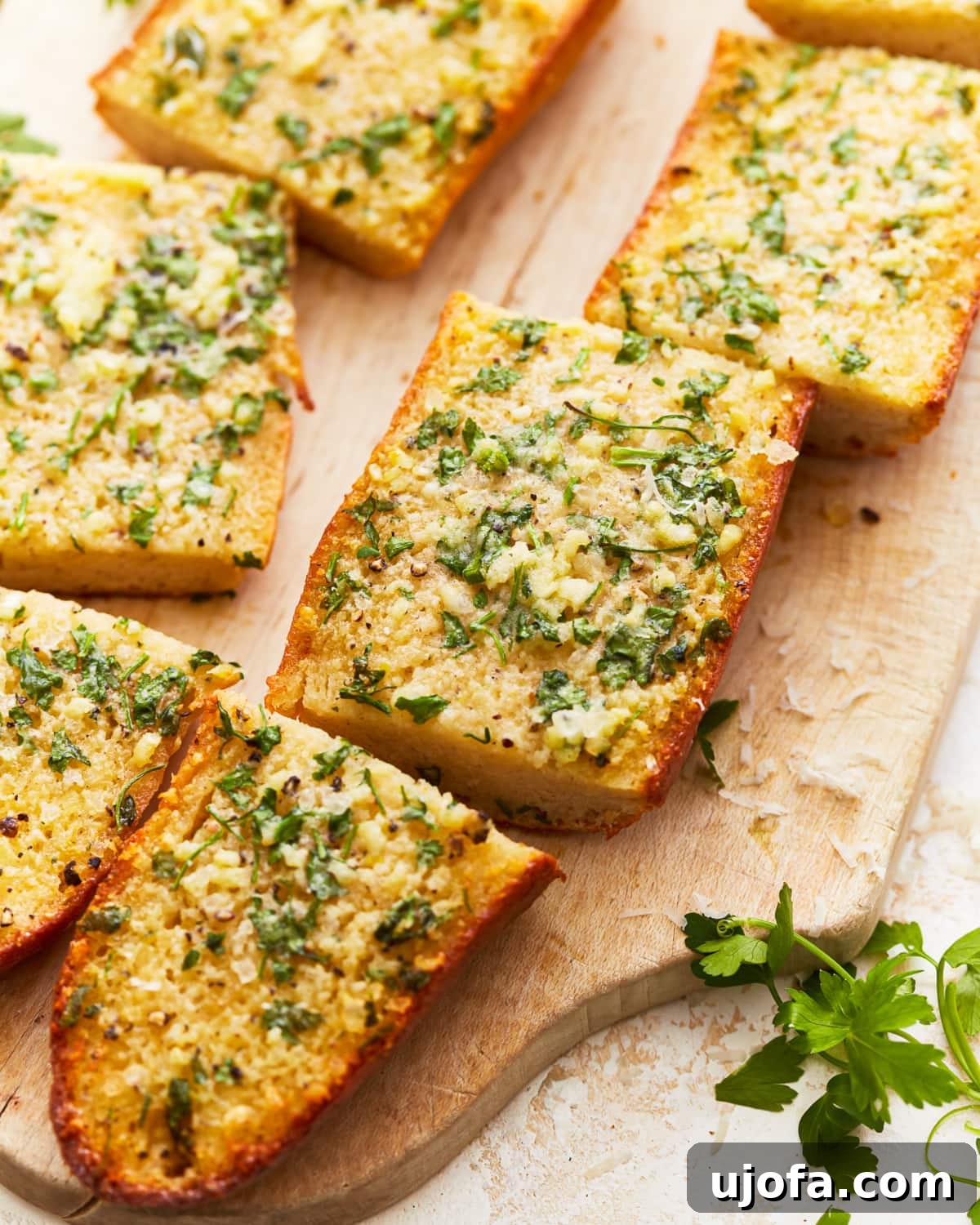 Aromatic Gluten-Free Garlic Bread 2 Gluten-free garlic bread sliced into individual pieces on a rustic wooden cutting board, ready to serve with a meal.