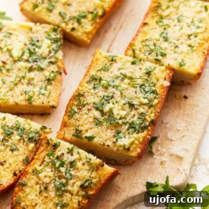 gluten-free garlic bread sliced into 6 pieces on a wooden cutting board.