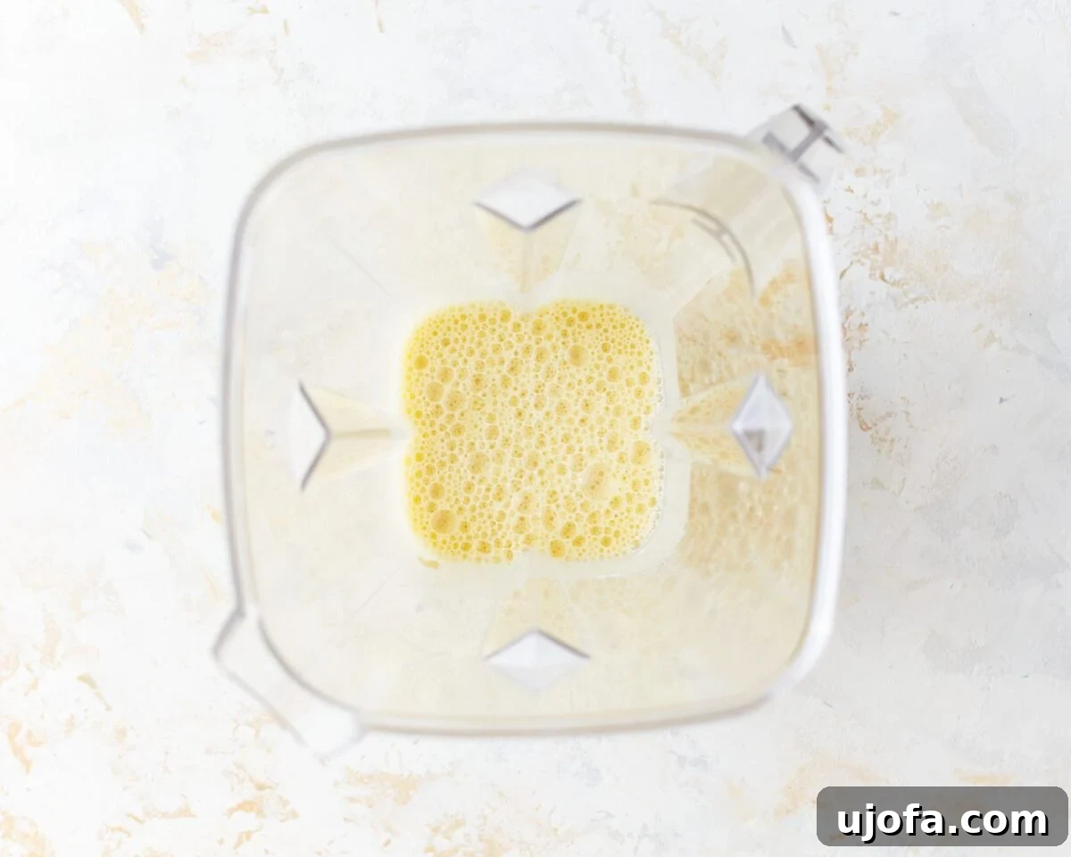 Overhead view of a blender filled with a smooth, frothy gluten-free Dutch baby batter, ready to be poured.